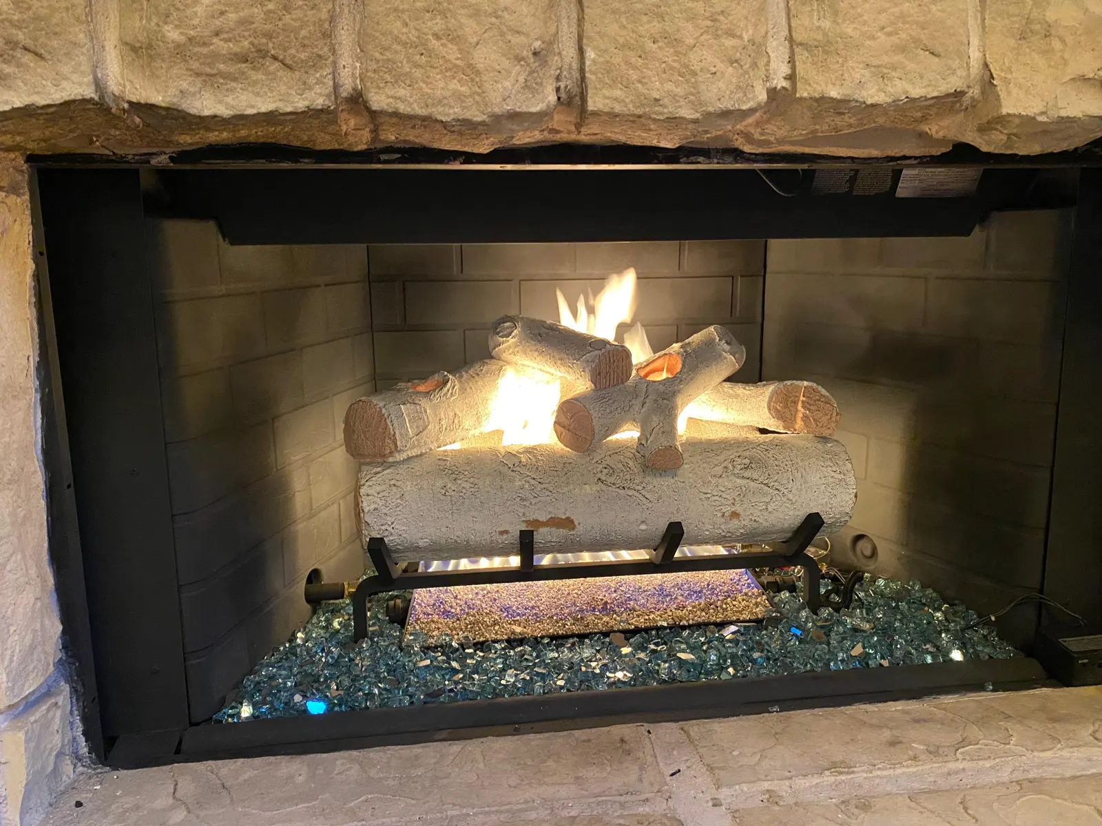 Gas logs lit in a stone fireplace